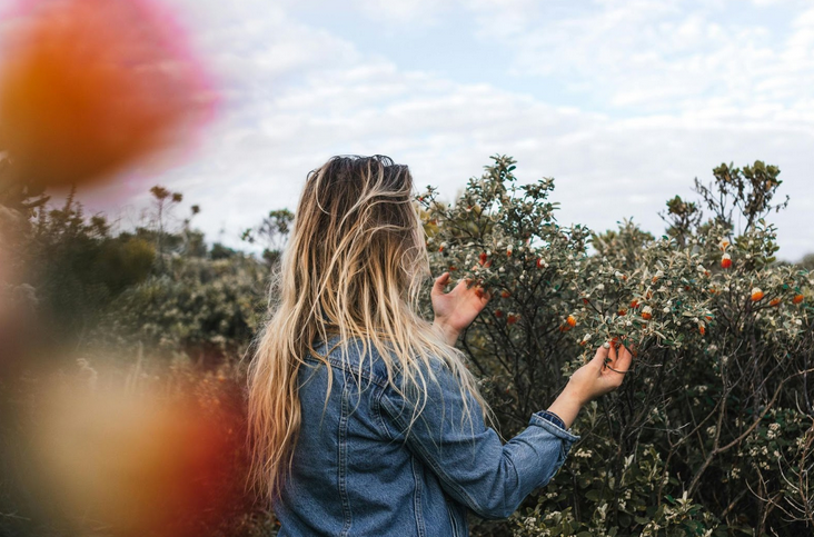 woman touching shrubs in countryside