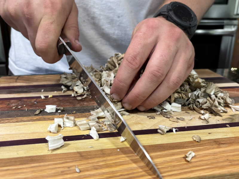 cutting Maitake Hen of the Woods mushrooms from Caputo & Guest on wood cutting board