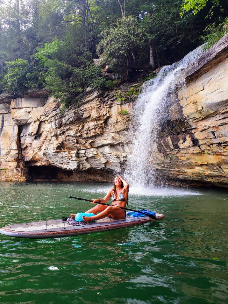 Kelly Bailey enjoying a stunning waterfall adventure on her paddleboard in a scenic Northeast Ohio location.