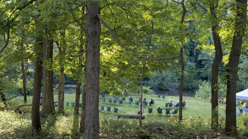 Shaded community seating area with green lawn chairs overlooking the river at Oxbow Meadows in CVNP.