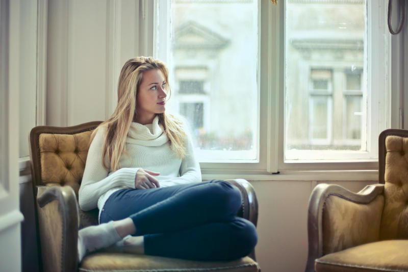 woman sitting on brown chair looking out window