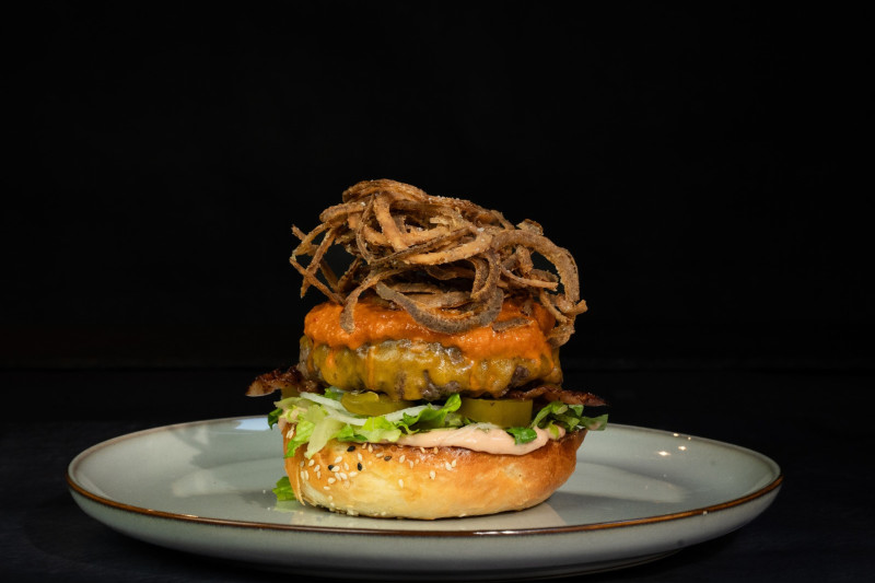 Photo of burger with onion fries by Kandalló Pub courtesy of burger Budapest.